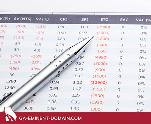 Silver pen on a financial spreadsheet with several items in red.