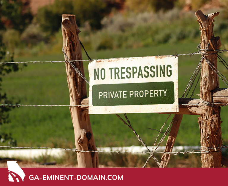 A sign on a wood & wire fence that reads NO TRESPASSING PRIVATE PROPERTY.