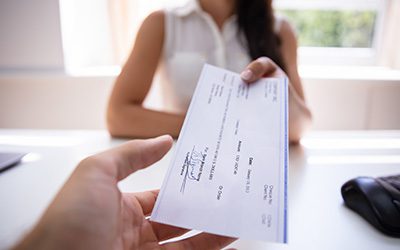 A businesswoman handing out a paper check.