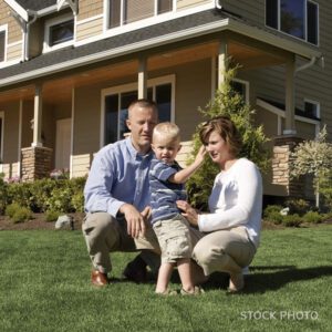 Family of three on the lawn in front of their house.