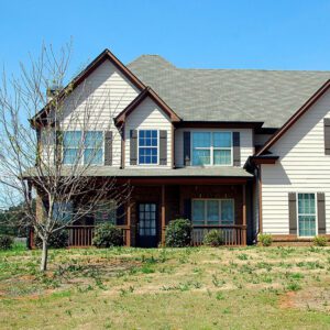 White house with dark roof and a tree in front.