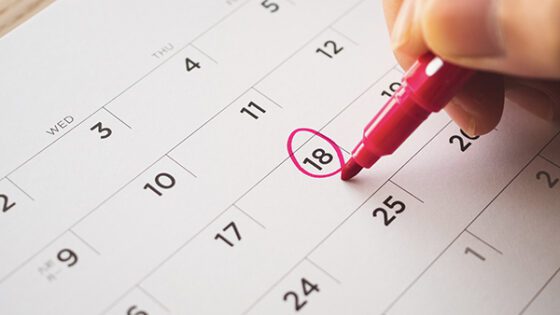 Circling a deadline in red pen on a calendar.