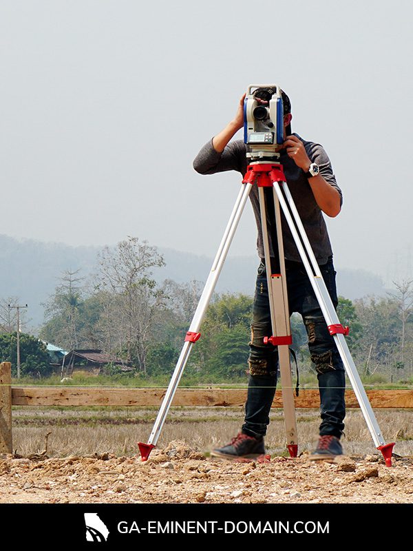 A land appraiser surveying a plot with a theodolite.